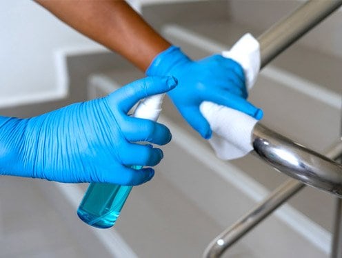 Staff member sanitizing a hallway surface