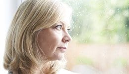 Woman looking out of a window at the rain