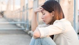 Woman with her hand on her head with her eyes closed