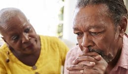 Depressed man with concerned woman sitting next to him