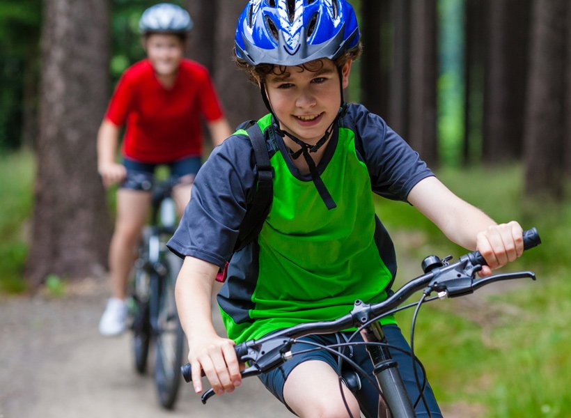 Child smiling and riding a bicycle with his helmet on.