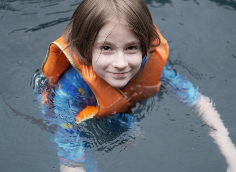 Child wearing a life jacket floating in the water