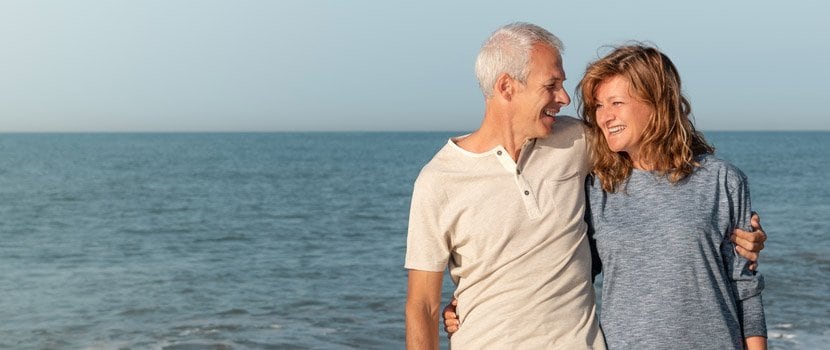 Man and woman walking on the beach and smiling at each other