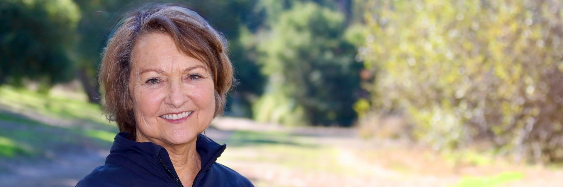 Cottage Health patient standing on a hiking trail and smiling at the camera