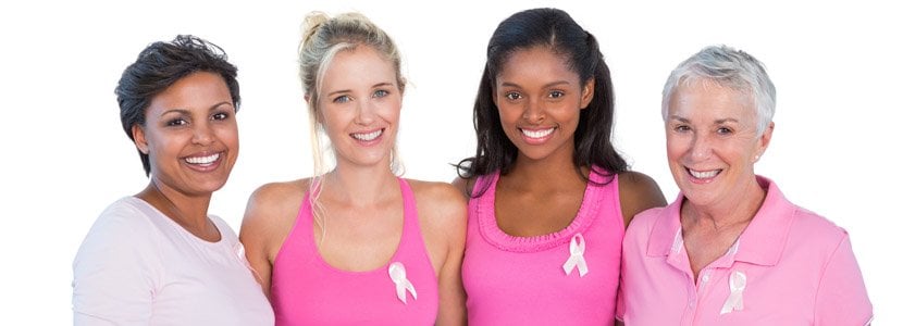 Women smiling and wearing pink ribbons