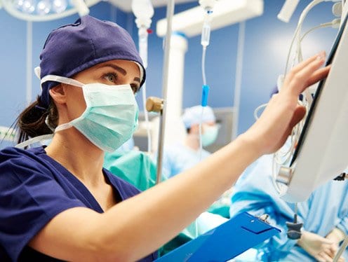 Clinician in a surgical room monitoring a computer screen